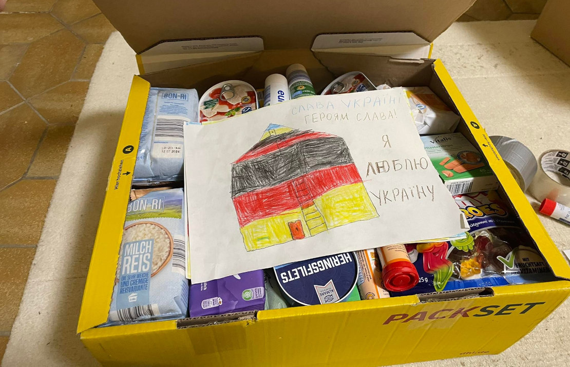 Paket mit Hilfsgütern für die Ukraine. DHL übernimmt die Versandkosten. Dabei ein Bild, das ein Flüchtlingskind gemalt hat.